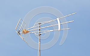 Old TV antenna on house roof with blue sky