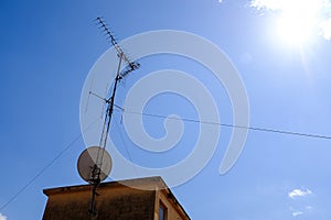 Old TV antenna on the top of a building roof on a blue sky