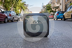 Old TV set on the city street with cars