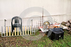 Old TV set and the rest of bulky trash. Old TV thrown away next to a wall with a pile of mixed garbage.