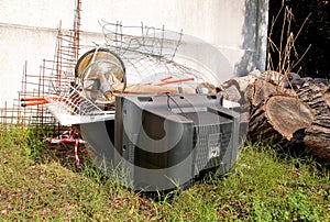 Old TV set and the rest of bulky trash. Old TV thrown away next to a wall with a pile of mixed garbage.