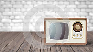 Old tv tunner on a wooden table against a white brick wall.