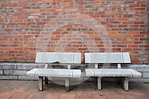 Old twin chairs near grungy red brick wall