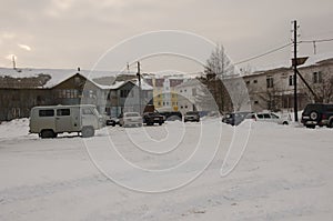 Old two-storied house in winter with snow, cars and trees on the yard. Poverty and misery, North