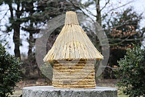 Old type beehive made of strew on a millstone. photo