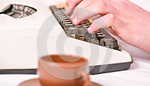 Old typewriter and authors hands. Male hands type story or report using white vintage typewriter equipment close up