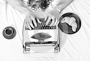 Old typewriter on bedclothes. Male hands type story or report using vintage typewriter equipment. Writing routine. No