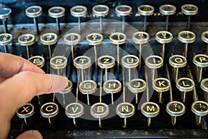 Old typewriter keyboard with fingers typing close-up