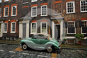 Old typical brick house in Shoreditch London with green vintage car