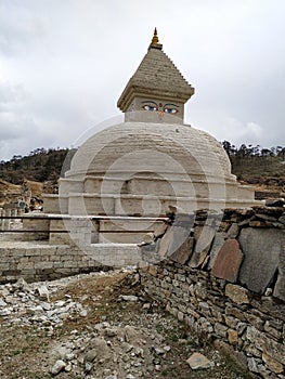 Old typical white Buddhist stupa in Himalaya mountains in cloudy weather