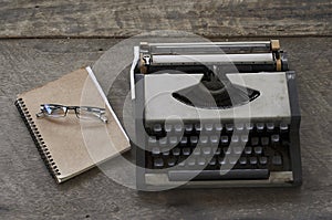 Old typing machine and glasses with book notes on wooden backgrounds