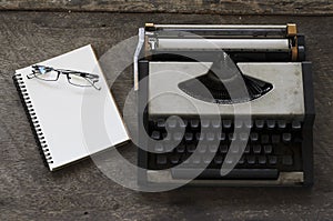 Old typing machine and glasses with notepad blank page