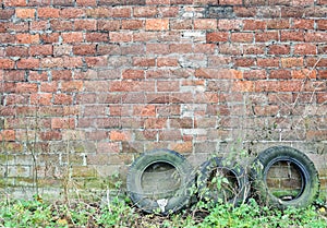 Old tyres in front of old brick wall