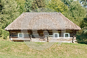 An old Ukrainian rural hut with a thatched roof on a sunny warm autumn day