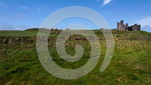 An old unfinished building on a green hill. Beautiful sky with clouds