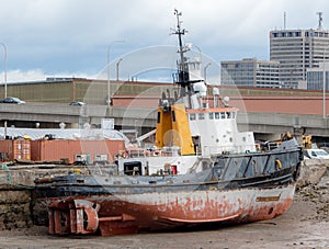 An old, unidentified tugboat resting at low tide