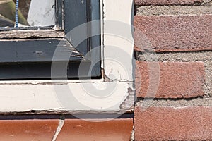 Old unmaintained part of a window frame. Paint is peeling off, rotten frame. Deferred maintenance