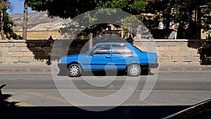 old unrecognizable blue car stands on street. bright blue retro car is parked near the sidewalk in city center, with car