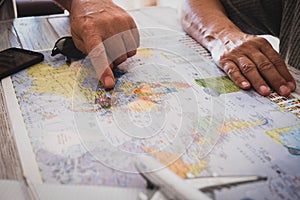 Old unrecognizable people planning a new travel - no limit age for wanderlust lifestyle - caucasian couple and world map with