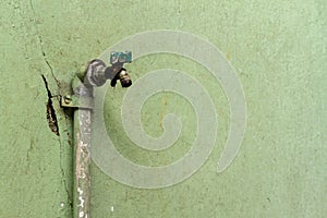 An old and untreated water faucet has a leak around the hole, making clean water consumption increase and wasted