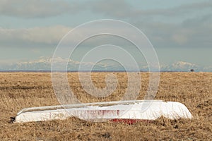 Old upturned small fishing boat on coastal grassland plains