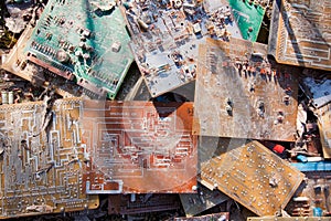 Old, used and broken electronic circuit chips thrown in the dirt; background texture photo