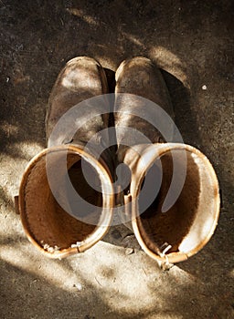 Old and used brown work boots, shot from above on a shed floor