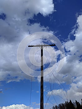 old and used electrical pole with wires against blue sky background