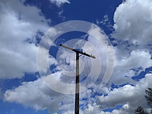 old and used electrical pole with wires against blue sky background