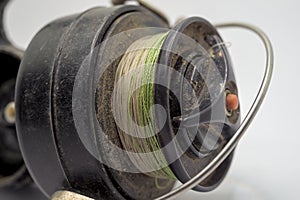 Old used fishing reel with line on the rod. Close up