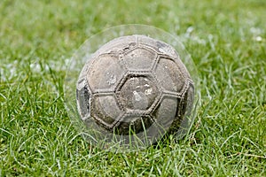 Old used football or soccer ball on field.