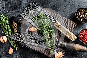 Old Used Meat Cleaver and knife with wooden cutting board. Black background. Top view