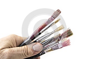 Old and used paint brushes with hand on white background.