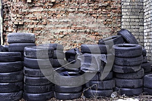 Old used tires stocked for recycling at red brick wall