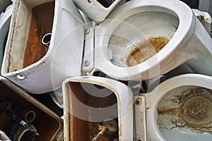 Old used toilet bowls lying on a dump