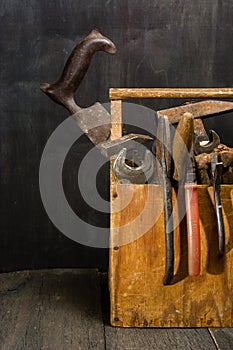 Old used tools in the toolbox. Dark background. spot lighting. Wooden box.
