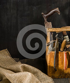 Old used tools in the toolbox. Dark background. spot lighting. Wooden box.