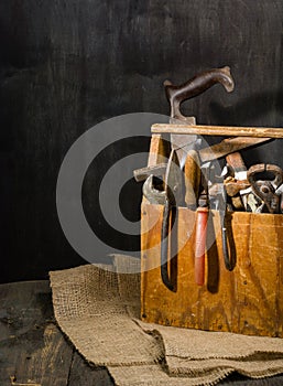 Old used tools in the toolbox. Dark background. spot lighting. Wooden box.