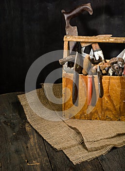 Old used tools in the toolbox. Dark background. spot lighting. Wooden box.