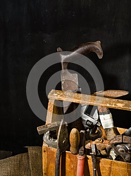 Old used tools in the toolbox. Dark background. spot lighting. Wooden box.