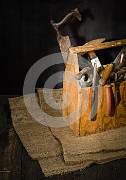 Old used tools in the toolbox. Dark background. spot lighting. Wooden box.