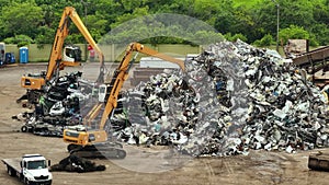 Old vehicle utilization junkyard with claw crane manipulator machines lifting and disposing cars for scrap metal