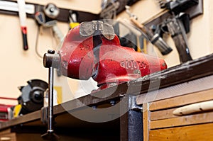 Old vice clamp in the workshop. Red rusty vise on the table.