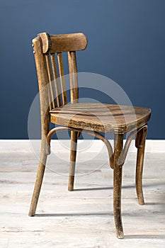 An old Viennese chair in a room against a dark blue wall and on a laminate