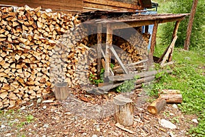 Old village house of a lumberjack with a pile of harvested firewood