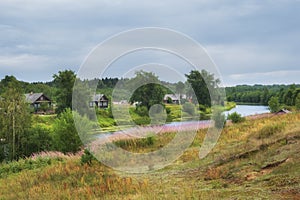 The old village of Saminsky Pogost with wooden houses on the banks of the river. Northern summer in countryside. Vologda region,