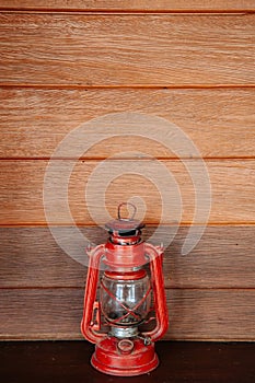 Old vinatge red kerosene oil lamp on wooden wall background