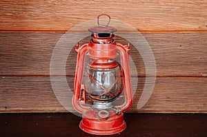 Old vinatge red kerosene oil lamp on wooden wall background