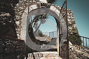 Old, vintage aged stone wall with arched opening gate and stairs up