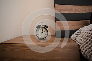 Old vintage alarm clock on a bedside table in bedroom